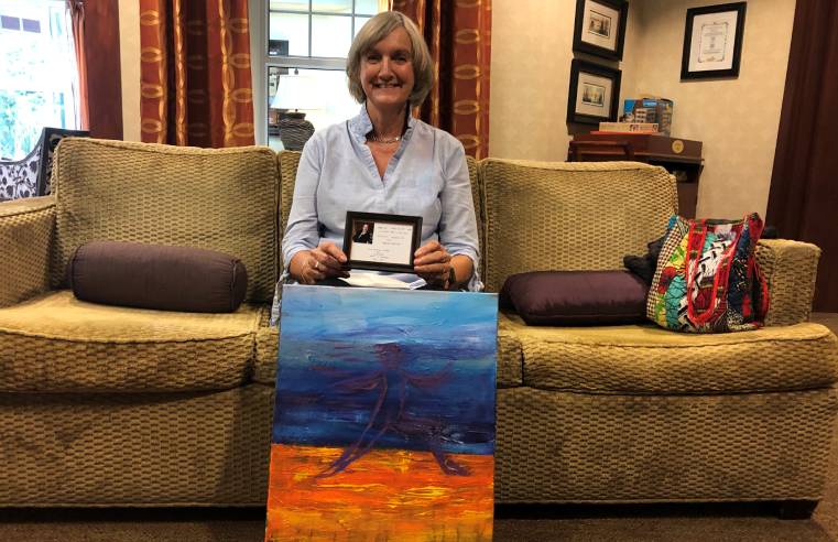 Lynne Mayo with her painting that celebrates the life and achievement of her brother Adrian Metcalfe