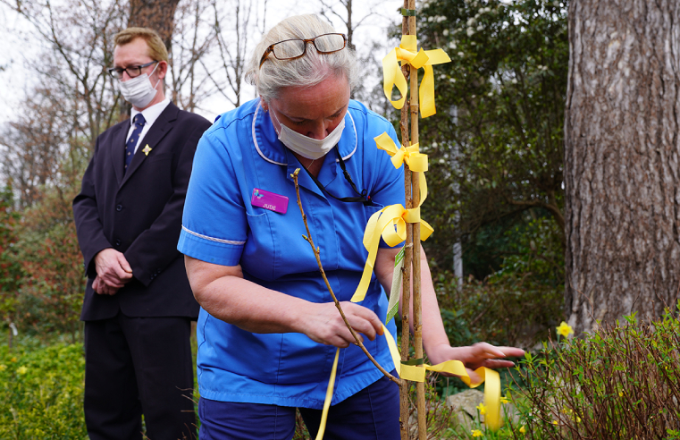 At the Surbiton Reflection service, Nurse Jude remembers residents that died by tying a ribbon to the tree. Image credit: Royal Star & Garter